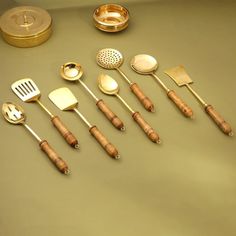 an assortment of kitchen utensils and spoons on a counter top with gold lids