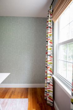 an empty room with wood floors and a curtain in front of a window that has geometric designs on it