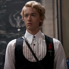 the young man is wearing a striped shirt and suspenders with a rose on his lapel