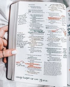 a person is holding an open bible in their hands with writing on the pages and handwritten numbers