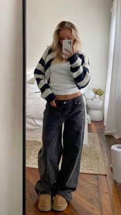 a woman taking a selfie in the mirror with her cell phone and jeans on