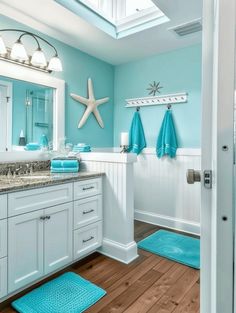 a bathroom with blue towels on the counter and white cabinets, along with starfish rugs