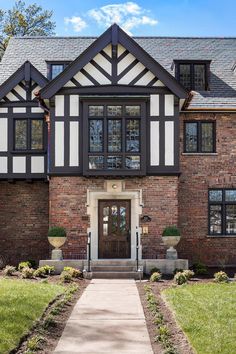 a large brick house with black and white trim on the windows, front door and walkway leading up to it