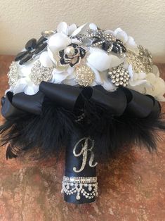 a bridal bouquet with black and white flowers, feathers and diapered brooches