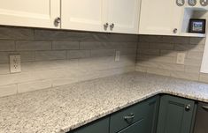 a kitchen with white cabinets and gray counter tops