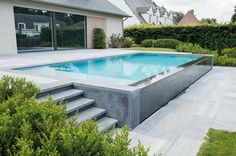 an empty swimming pool with steps leading up to it and a house in the background