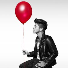 a man sitting on the ground holding a red balloon