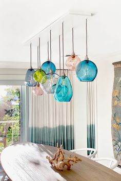 a dining room table and chairs with hanging glass globes on the ceiling above it