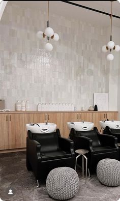 a salon with black chairs and white sinks