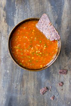 a bowl of soup with tortilla chips on the side and salsa in it