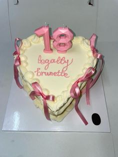 a heart shaped birthday cake with pink ribbon on it's edges and the number eighteen