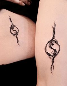 two women's legs with tattoo designs on their butts, one is black and the other is white