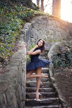 a woman in a blue dress is standing on some stairs and posing for the camera