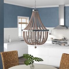 a chandelier hanging from the ceiling in a kitchen with blue walls and wicker chairs