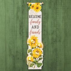 a sign that says welcome family and friends with sunflowers hanging on a green wooden wall