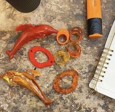 an assortment of objects are laying on the ground next to a notepad and pen