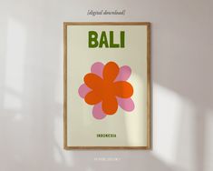 a framed poster hanging on the wall in front of a white wall with an orange and pink flower