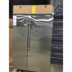 a stainless steel double door refrigerator in a warehouse