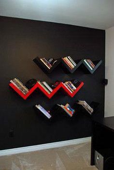 a room with black walls and red bookshelves on the wall in front of it