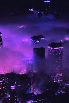 an aerial view of skyscrapers in the city at night with purple lights and fog