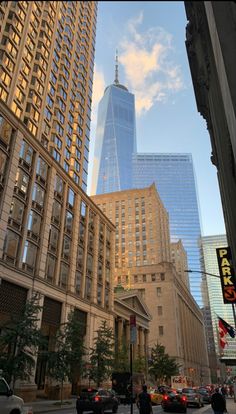 tall buildings in the city with people walking on the sidewalk and cars driving down the street