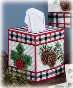 the tissue box is decorated with holly and pine cones on it's plaid cover