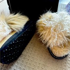 a pair of furry slippers sitting on top of a floor next to a suitcase