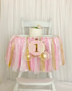 a pink and gold 1st birthday party with a cake on a table, decorated chair