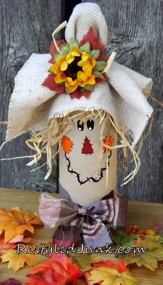 a scarecrow head is made out of burlock and hay with fall leaves around it