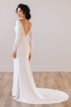 a woman in a white wedding dress standing on a wooden floor with her back to the camera