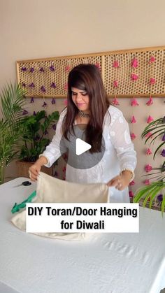 a woman standing over a table with a cloth bag on it and the words diy toran / door hanging for diwali