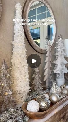 a mantel decorated with silver and white christmas trees, ornaments and candles in front of a mirror