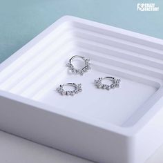 three pairs of earrings sitting on top of a white tray