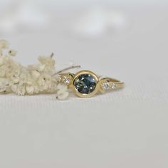 This unique design of modern boho 0.85c parti sapphire engagement ring is truly magical. Inspired by the moon shapes of its orbit cycle, it features a stunning round natural multi-colored parti sapphire captured in a raw bezel circle setting. The 14k yellow gold band is designed with two decorative side boho half moons and 4 side diamonds, making this beauty a one to remember! Perfect for the modern bohemian bride, this ring is sure to be a conversation starter. This ring is ready to ship in US Round Sapphire Ring With Bezel Setting, 14k Gold Celestial Sapphire Ring, Celestial Yellow Gold Sapphire Ring, Celestial Style Sapphire Ring For Anniversary, Celestial Sapphire Ring For Anniversary, Celestial Style Round Sapphire Ring, Unique Sapphire Ring With Rose Cut Diamonds, Half Moons, Parti Sapphire