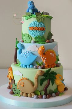 a three tiered cake decorated with dinosaurs