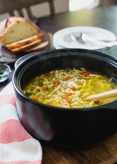 a bowl of soup on a table with bread in the background