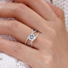 a woman's hand with a diamond ring on her finger and a white sweater