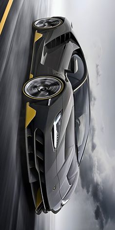 a grey and yellow sports car driving down the road with clouds in the back ground