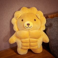 a yellow stuffed animal sitting on top of a wooden table next to a gray pillow