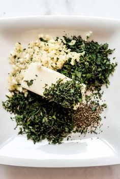 herbs and cheese are on a white plate