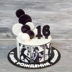 a white and black birthday cake with balloons on the top is decorated with an image of two people