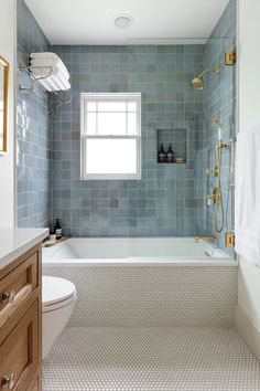 a bathroom with blue tile walls and white fixtures, including a bathtub in the center