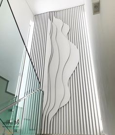 a glass staircase leading up to a white wall with an abstract sculpture on it's side