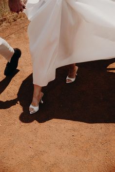 a woman in white dress walking down a dirt road