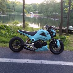 a blue motorcycle parked on the side of a road next to a body of water