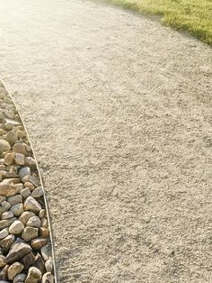 a bench sitting on the side of a road next to a pile of rocks and grass