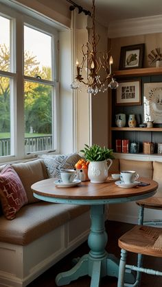 a table with two cups on it in front of a window and some bookshelves