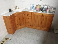 the corner of a bathroom with wooden cabinets and tile flooring is shown in this image