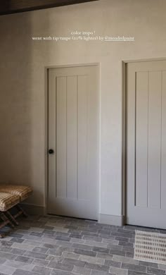 a room with two doors and a bench on the floor in front of one door