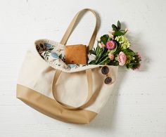 a tote bag with flowers and sunglasses on the side, hanging from a hook